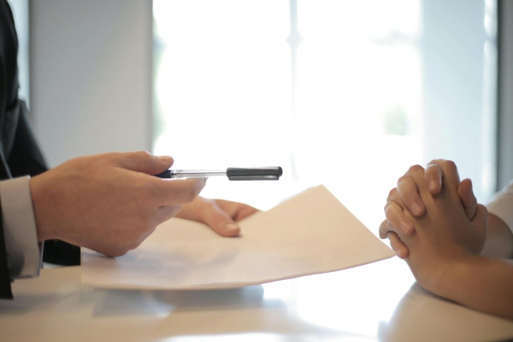 A hand holding a pen and paper