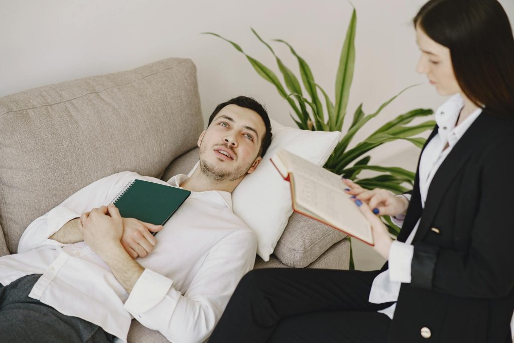 A man on the bed talking to a therapist.